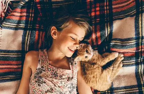 kitten laying in bed with girl